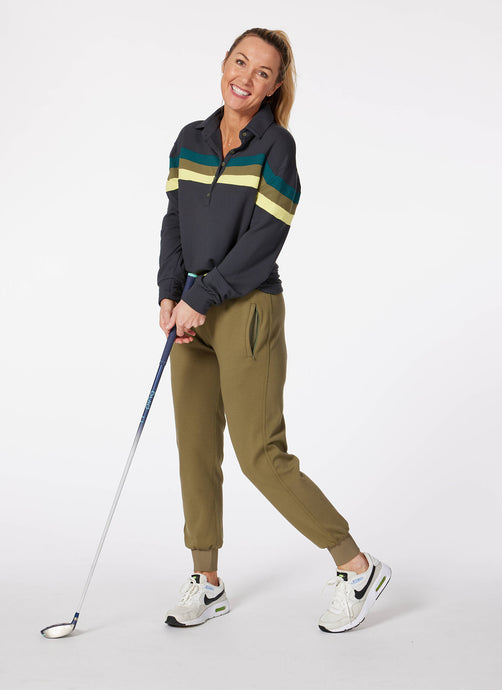 Model wearing olive women's golf joggers and black murray golf shirt holding a golf club.