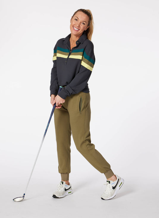 Model wearing olive women's golf joggers and black murray golf shirt holding a golf club.
