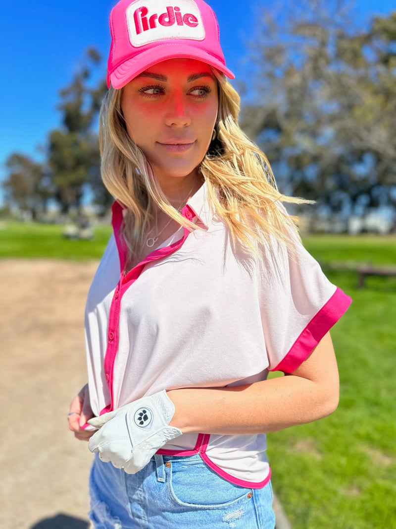 Load image into Gallery viewer, Pink Caddy Camp golf shirt on a model also wearing a pink Pirdie golf trucker hat and jean shorts on a golf course.
