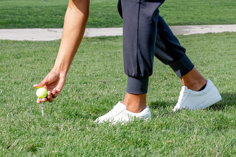Load image into Gallery viewer, Woman teeing up a ball on the golf course wearing black ace golf joggers.

