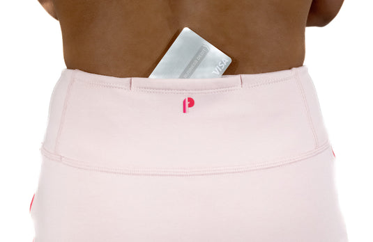 Model wearing a dusty rose Foreplay golf skirt showing the back detail of a small pocket holding a credit card.