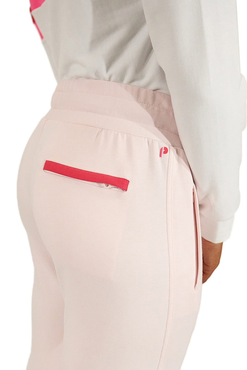 Load image into Gallery viewer, Model wearing pink women&#39;s golf joggers highlighting pocket contrast in a studio shot.
