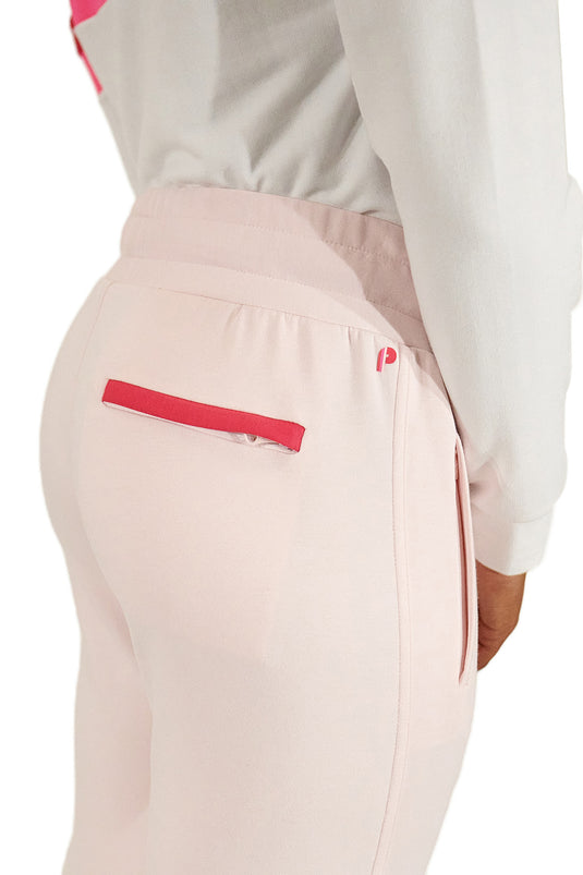 Model wearing pink women's golf joggers highlighting pocket contrast in a studio shot.